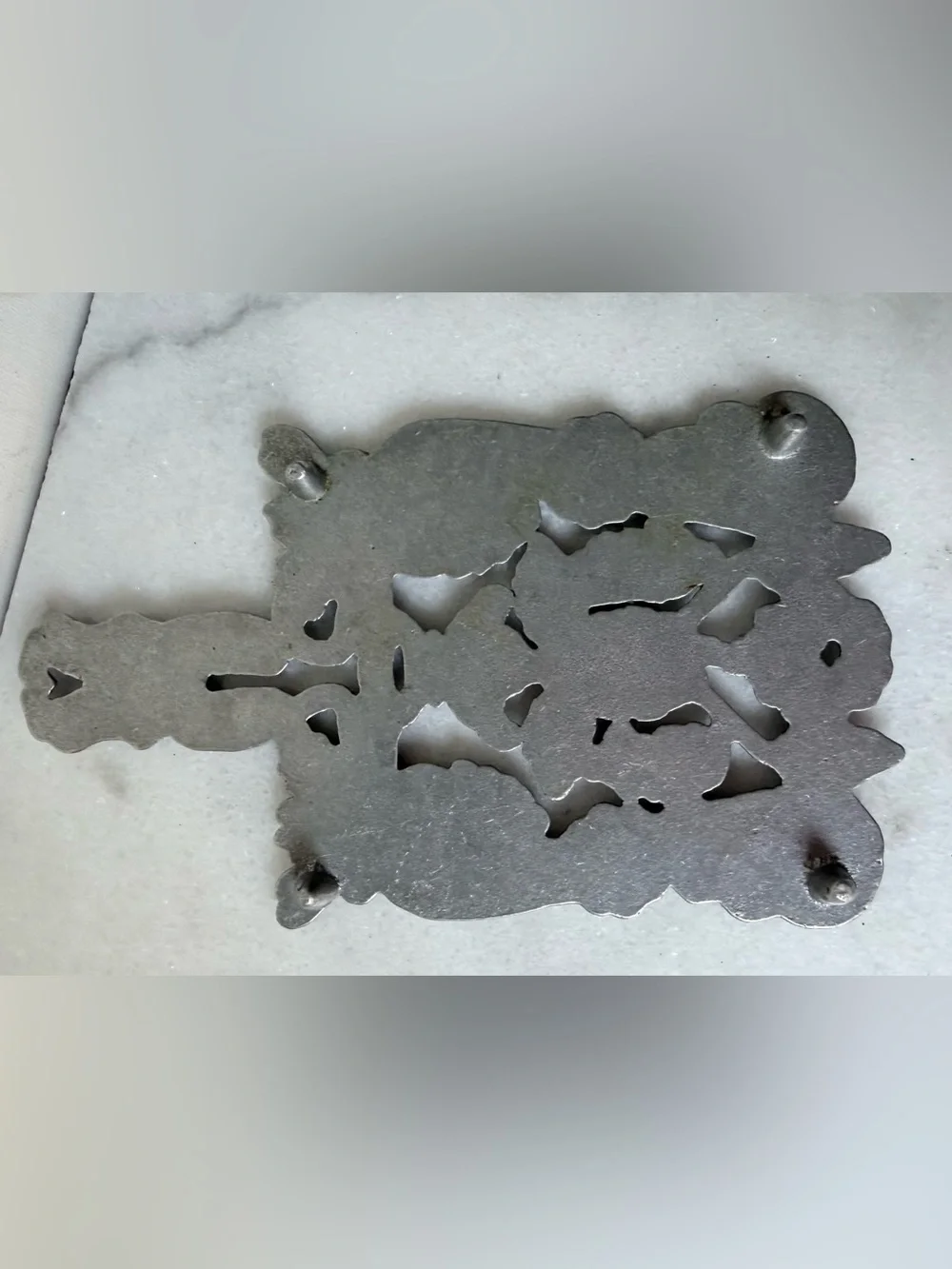 vintage silver-toned metal trivet featuring a decorative design grapes scrolls.